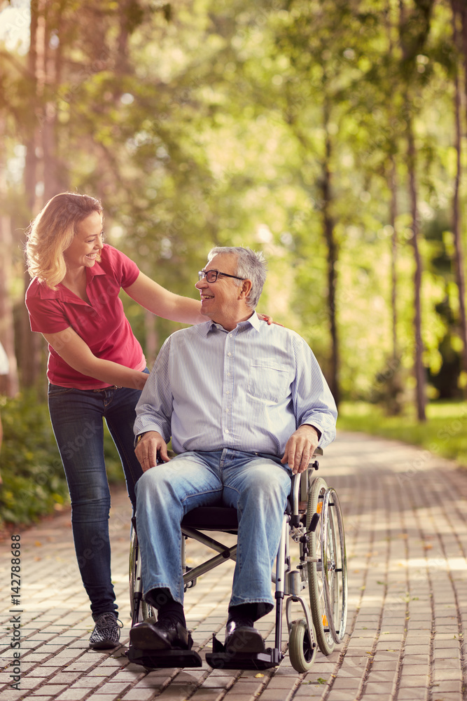 Smiling young woman with her disabled father in wheelchair. Smiling young woman with her disabled father in wheelchair.