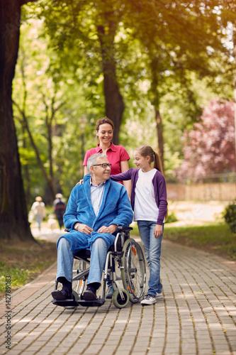 Disabled man in park spending time together with his daughter and granddaughter.