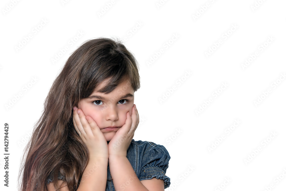 Portrait of disappointed brunette long haired little girl isolated on the white background. The girl is holding her face by both hands. Portrait of disappointed brunette long haired little girl isolated on the white background. The girl is holding her face by both hands.