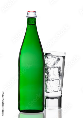 Green bottle of sparkling mineral water with glass