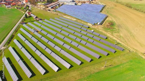 Camera flight over a solar power plant in agricultural landscape. Industrial background on renewable resources theme. Industry of power and fuel generation in European Union.  photo