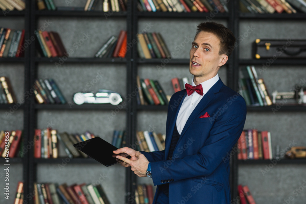 Fototapeta premium young businessman in blue suit emotional posing with tablet