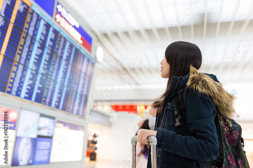 Woman looking at information board and checking her flight