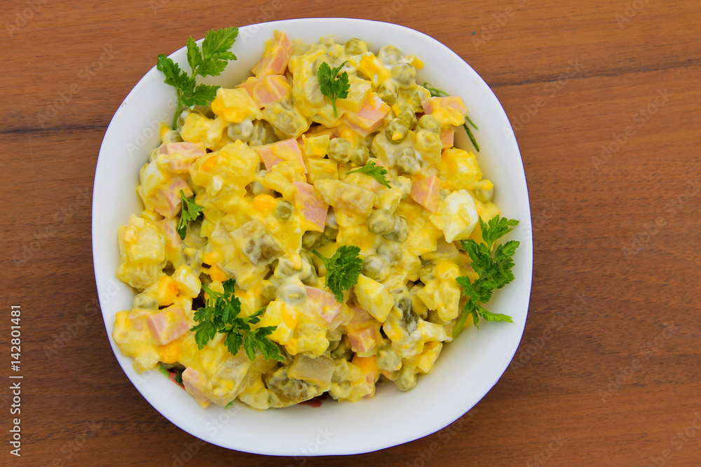 Russian traditional salad olivier on wooden table Russian traditional salad olivier on wooden table