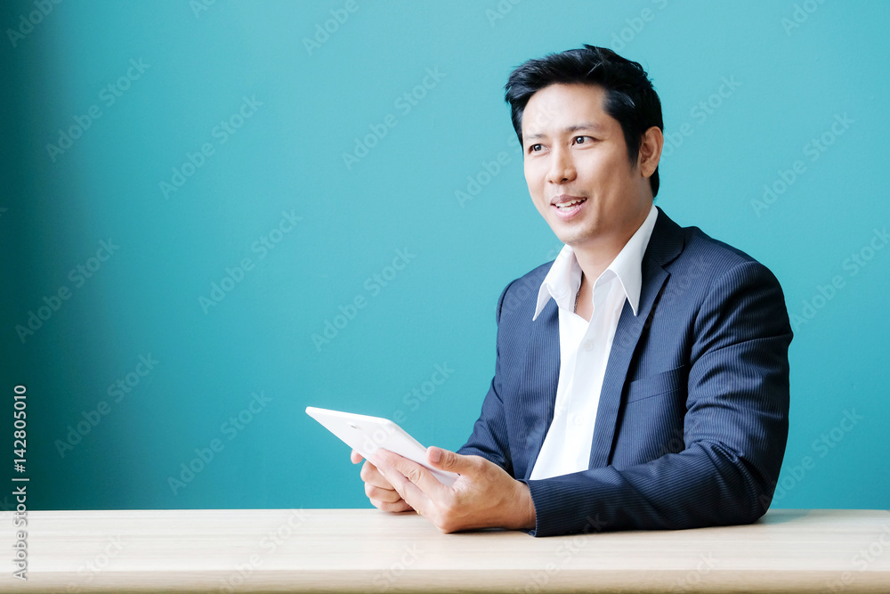 Asian business man using digital tablet while sitting at office table, business and technology Asian business man using digital tablet while sitting at office table, business and technology