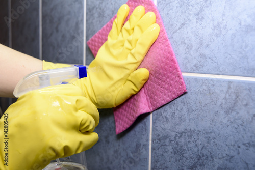 Scrubbing tiles in the kitchen with yellow gloves
