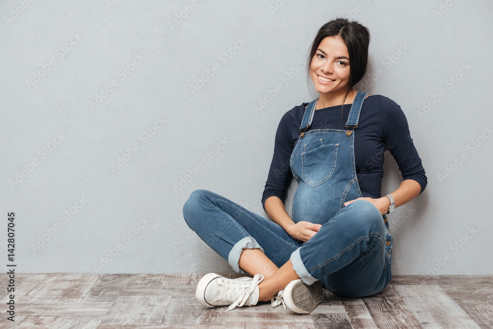 Cheerful pregnant lady sitting on floor Cheerful pregnant lady sitting on floor