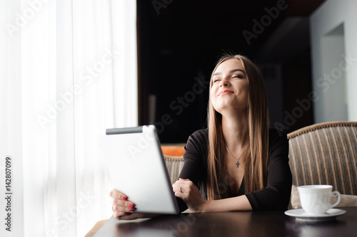 Beautiful pregnant woman using digital tablet at table in cafe