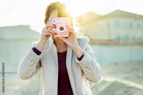 Young woman shooting with pink instant camera