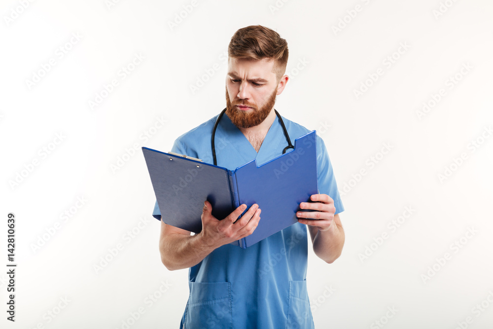 Pensive medical doctor or nurse with stethoscope looking at clipboard Pensive medical doctor or nurse with stethoscope looking at clipboard