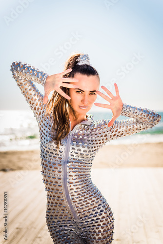 Girl in a shiny suit and a tall tail against the sea