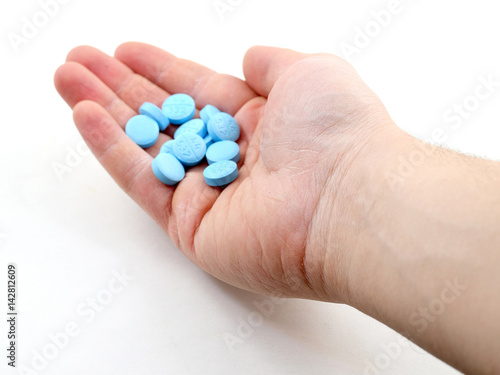Male hand holding plue pills