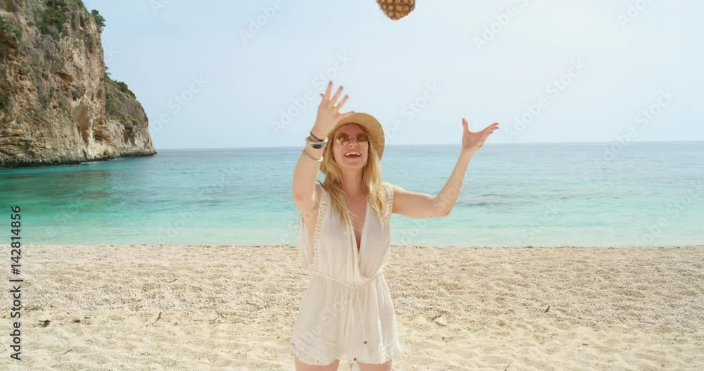 Happy woman balancing pineapple on head posing for camera being silly and playful on tropical beach summer vacation holiday Happy woman balancing pineapple on head posing for camera being silly and playful on tropical beach summer vacation holiday