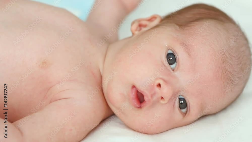 boy's face, the newborn child looking out the window at the light and lying on the white sheet boy's face, the newborn child looking out the window at the light and lying on the white sheet
