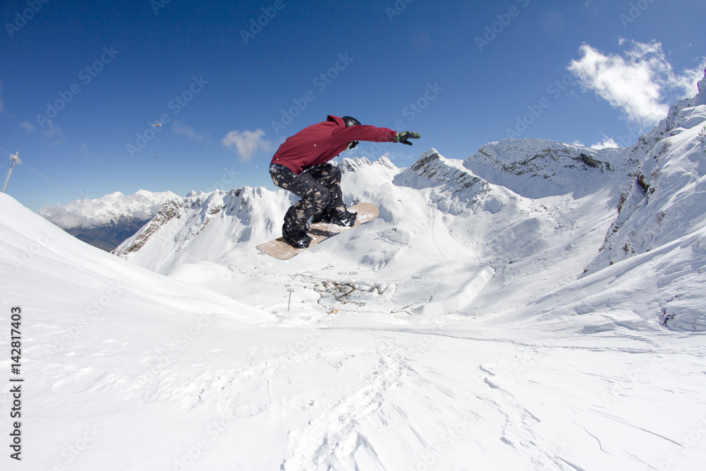 Snowboarder jumps in mountains, winter extreme sport.