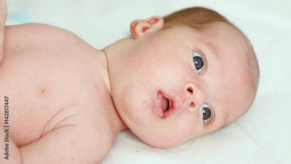 boy's face, the newborn child looking out the window at the light and lying on the white sheet boy's face, the newborn child looking out the window at the light and lying on the white sheet