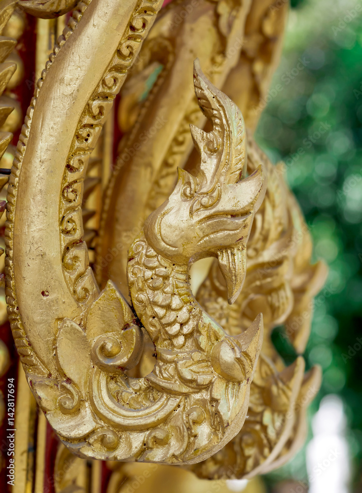 Wood carving is a golden serpent in Thai temple.