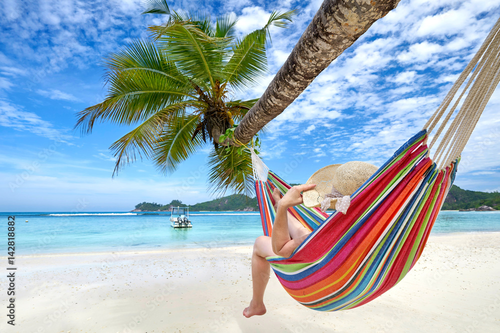 Frau in einer Hängematte im Urlaub am Strand Stock-Foto | Adobe Stock