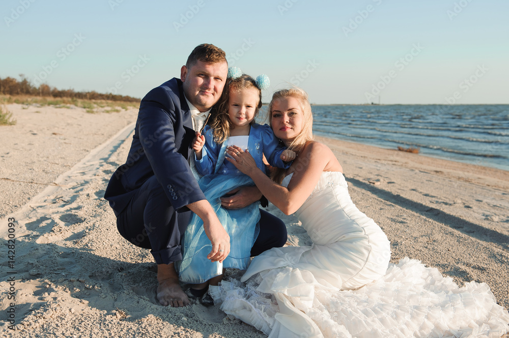 Happy family on a beach at sunrise - child mother and father
