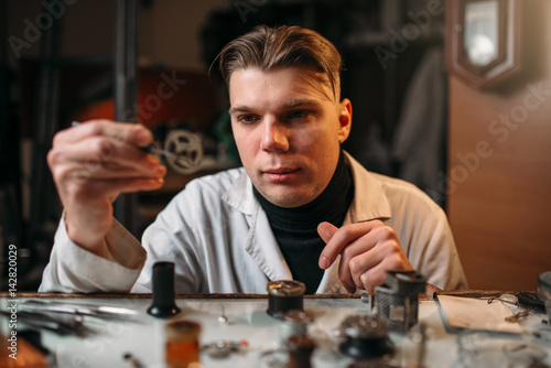 Watchmaker holding with tweezers a gear of hours © Nomad_Soul