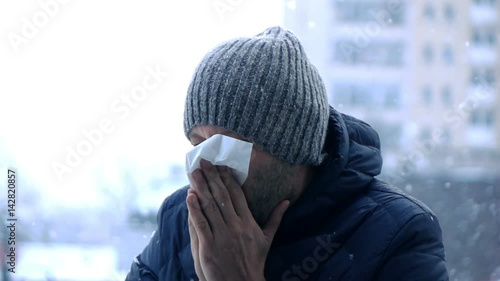 Young man blowing his nose the winter, super slow motion
