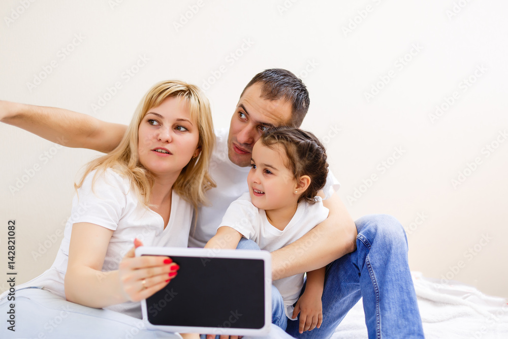 Happy family with sweet baby play with computer tablet on a white background. Early development and learning toys. Happy family with sweet baby play with computer tablet on a white background. Early development and learning toys.