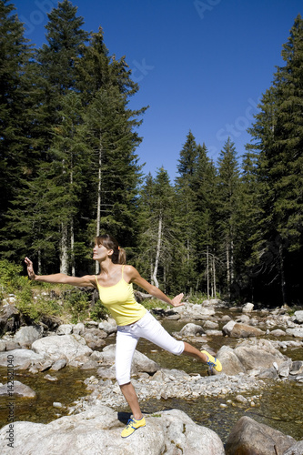 femme qui fait du yoga au bord d'une rivière dans la forêt