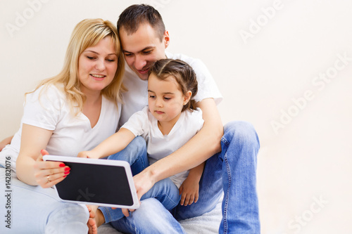 Young happy family running on a laptop. Family of three people looking at a computer screen. Mom, dad and daughter make purchase in the online store.