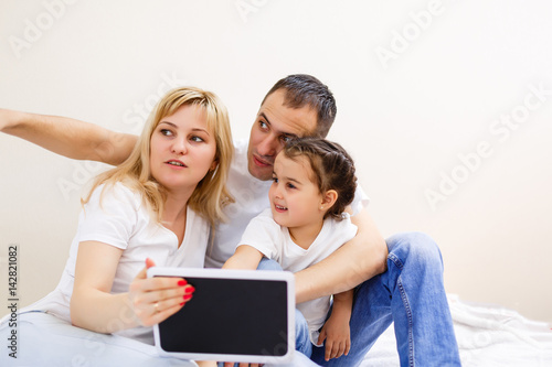 Happy family with sweet baby play with computer tablet on a white background. Early development and learning toys.