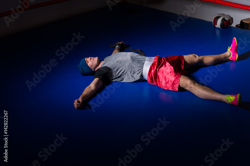 Young sporty boxer in sportswear lying and resting after workout