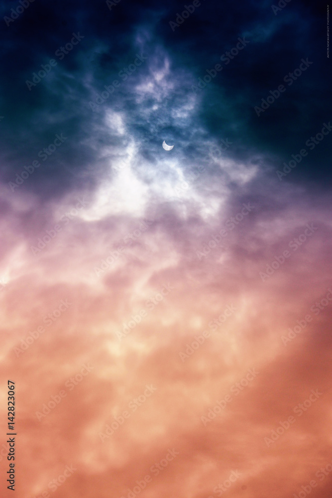 Partial solar eclipse seen through a layer of clouds.