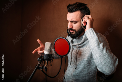 Male singer recording a song in music studio