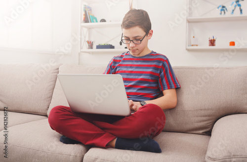 Teenage boy using laptop on couch at home