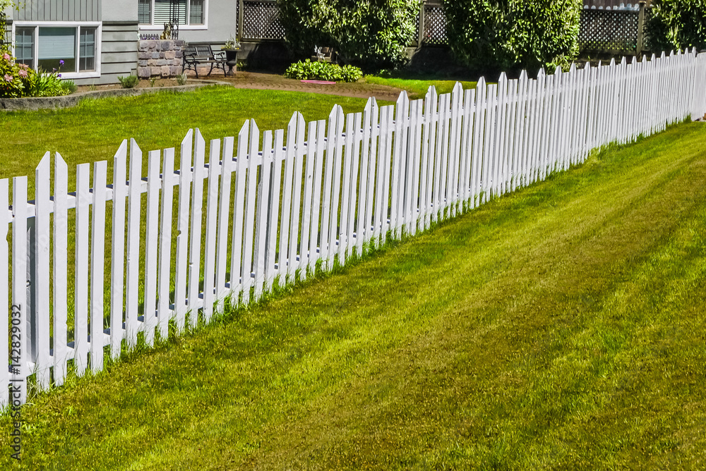 Accurate white wooden fence along the front yard of residential house
