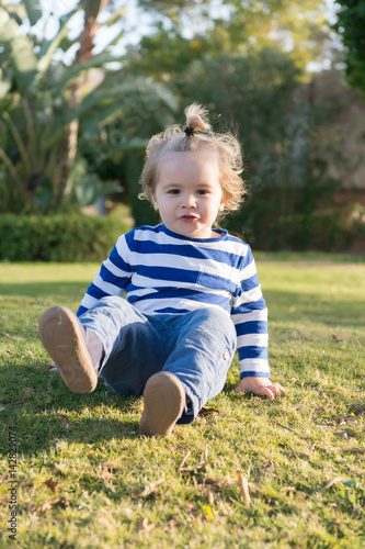small baby boy with happy face on green grass barefoot © be free