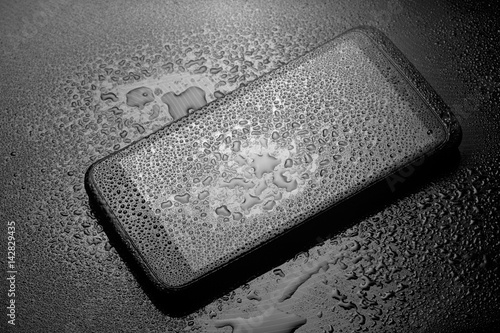 Wet smartphone with water drops on dark background