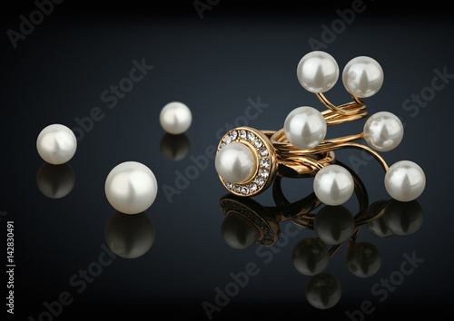 Golden rings with diamonds and pearls on black background