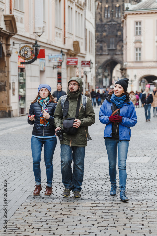 Fototapeta premium group of happy smiling multiracial friends walking and have fun in the old city of prague. Travel with friends concept