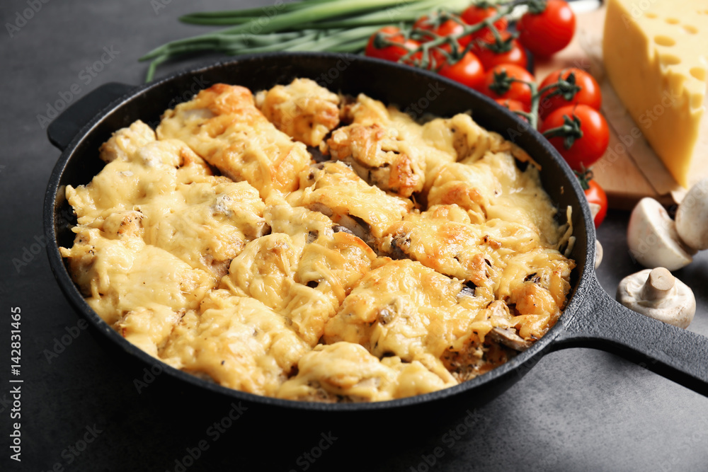 Roasted chicken with cheese in frying pan on kitchen table Roasted chicken with cheese in frying pan on kitchen table