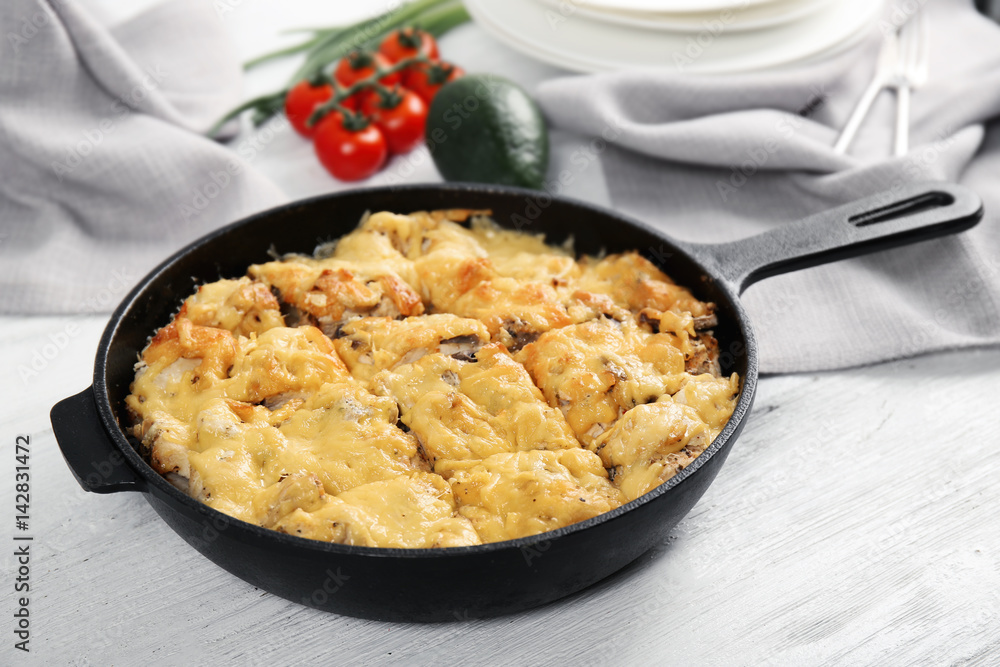 Roasted chicken with cheese in frying pan on kitchen table