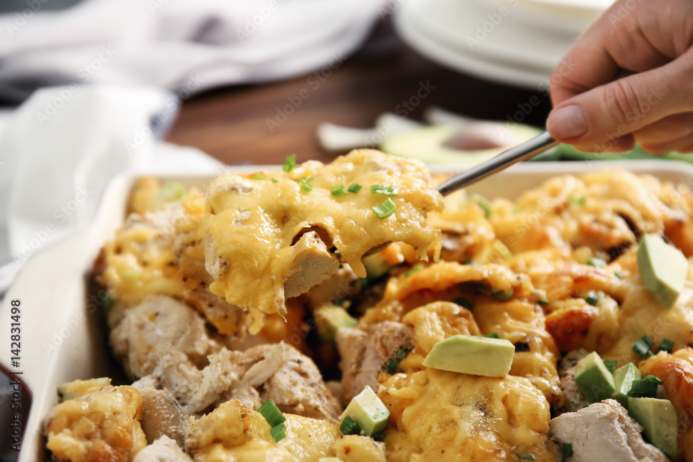 Woman taking portion of roasted chicken with cheese from casserole dish Woman taking portion of roasted chicken with cheese from casserole dish
