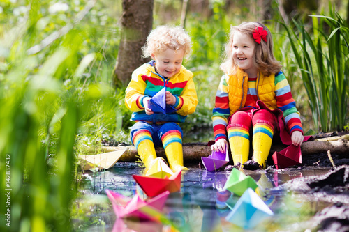 Kids playing with colorful paper boats in a park