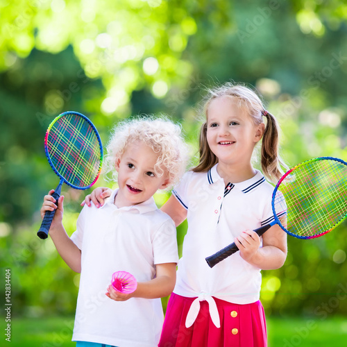 Kids play badminton or tennis in outdoor court © famveldman