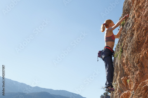 A young girl climber climbs high up the cliff in Geyikbayiri Tur
