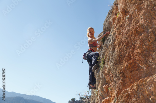 A young girl climber climbs high up the cliff in Geyikbayiri Tur