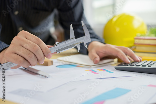 architect work concept.man working with new startup project in modern loft. Drawning pen,inspection engineer report with product and vernier calipers,engineer architectural project,Notebook on table