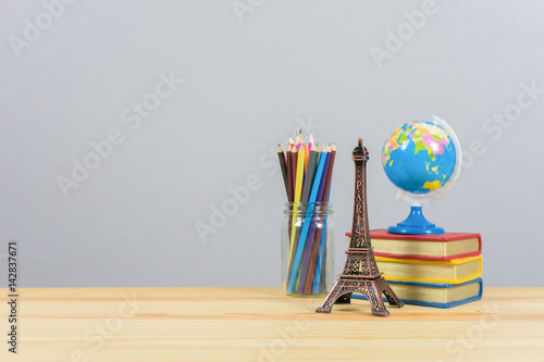 Eiffel tower statue and stack of book and globe on the school desk, book of knowledge school background education,a stack of old battered book with empty space to the left. photo
