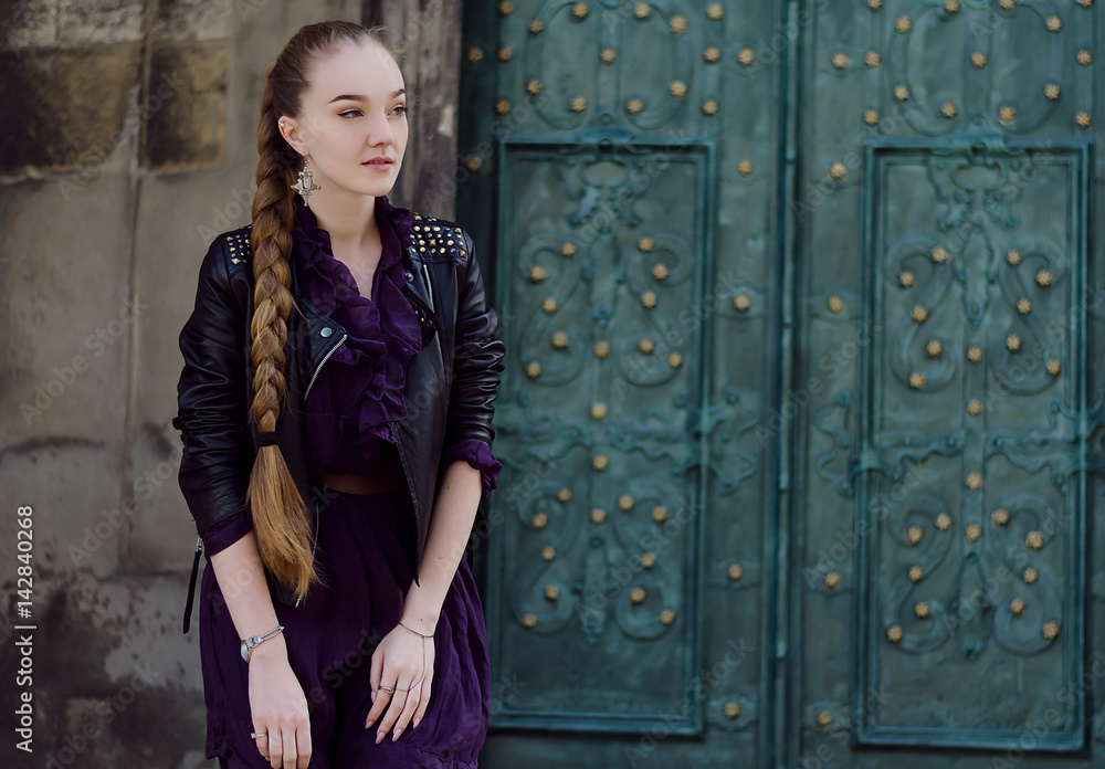 Fototapeta premium Outdoor portrait of young beautiful woman with long hair, green doors in the background
