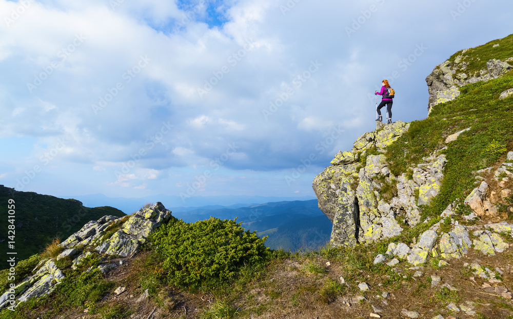 Sporty girl at the edge of precipice high on the mountains