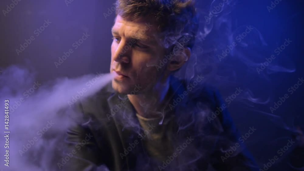 young man vaping with an electronic cigarette and make some smoke clouds young man vaping with an electronic cigarette and make some smoke clouds